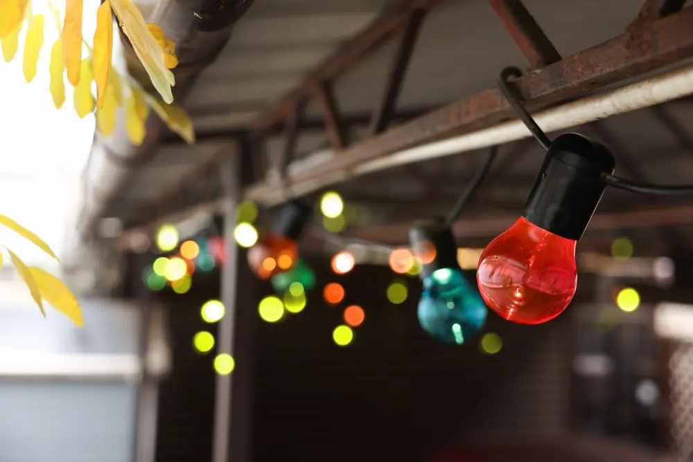 Christmas celebration. Canopy decorated with colorful light bulbs outdoors, closeup.