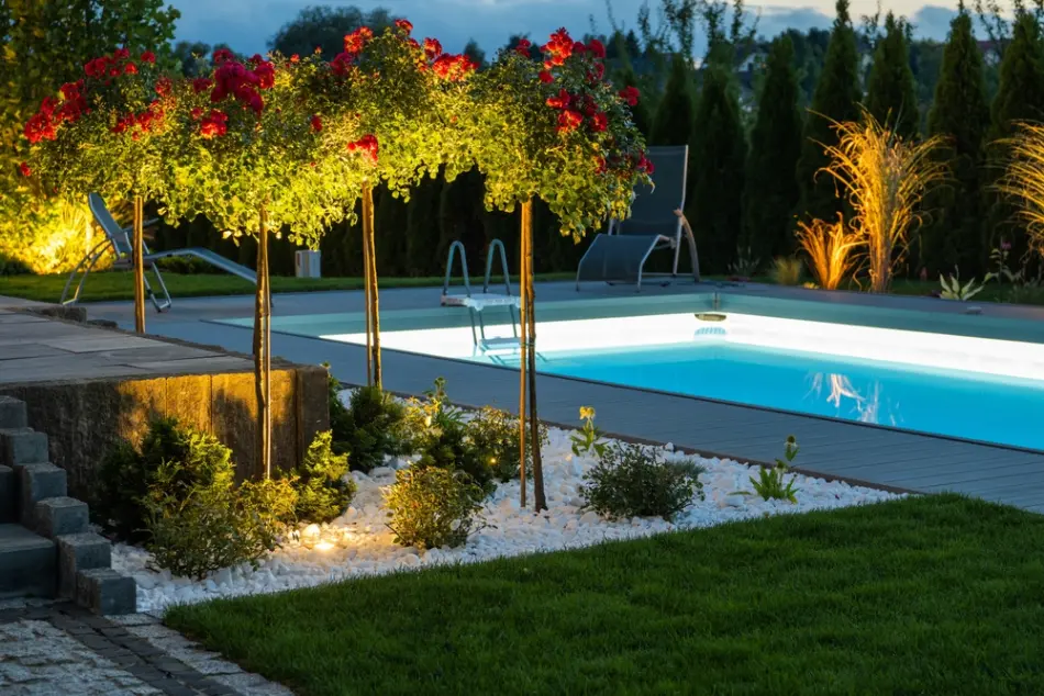 Modern illuminated residential outdoor swimming pool, poolside and the back yard.