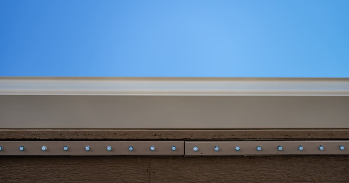 A line of LED permanent lights are installed on the underside of a roof. A bright blue sky is in the background.